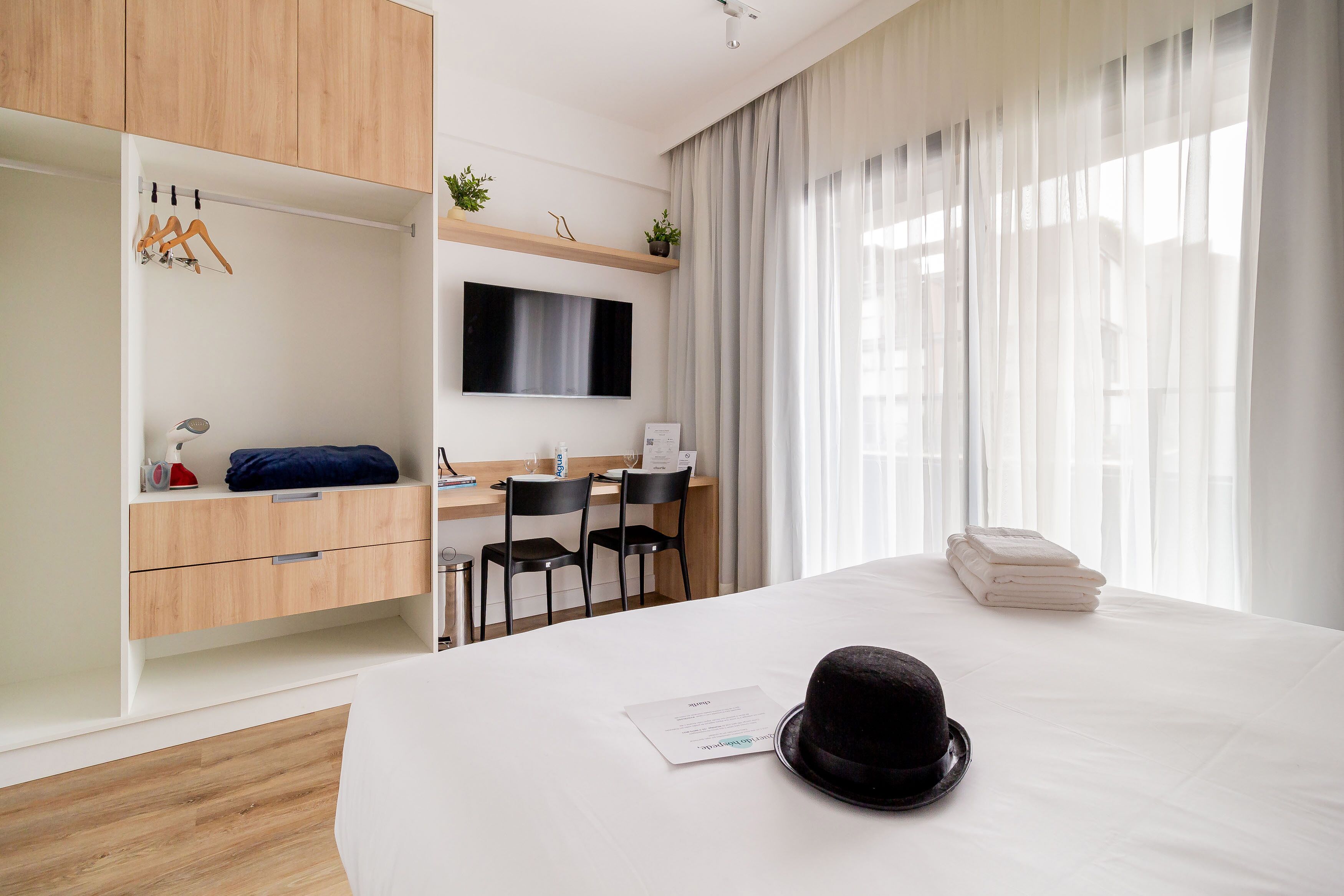 A modern hotel room with a bed, a desk, and a TV.