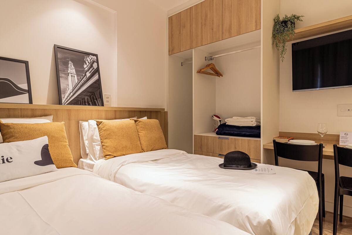 Ein Hotelzimmer mit zwei Betten, einem Schreibtisch und einem Fernseher.