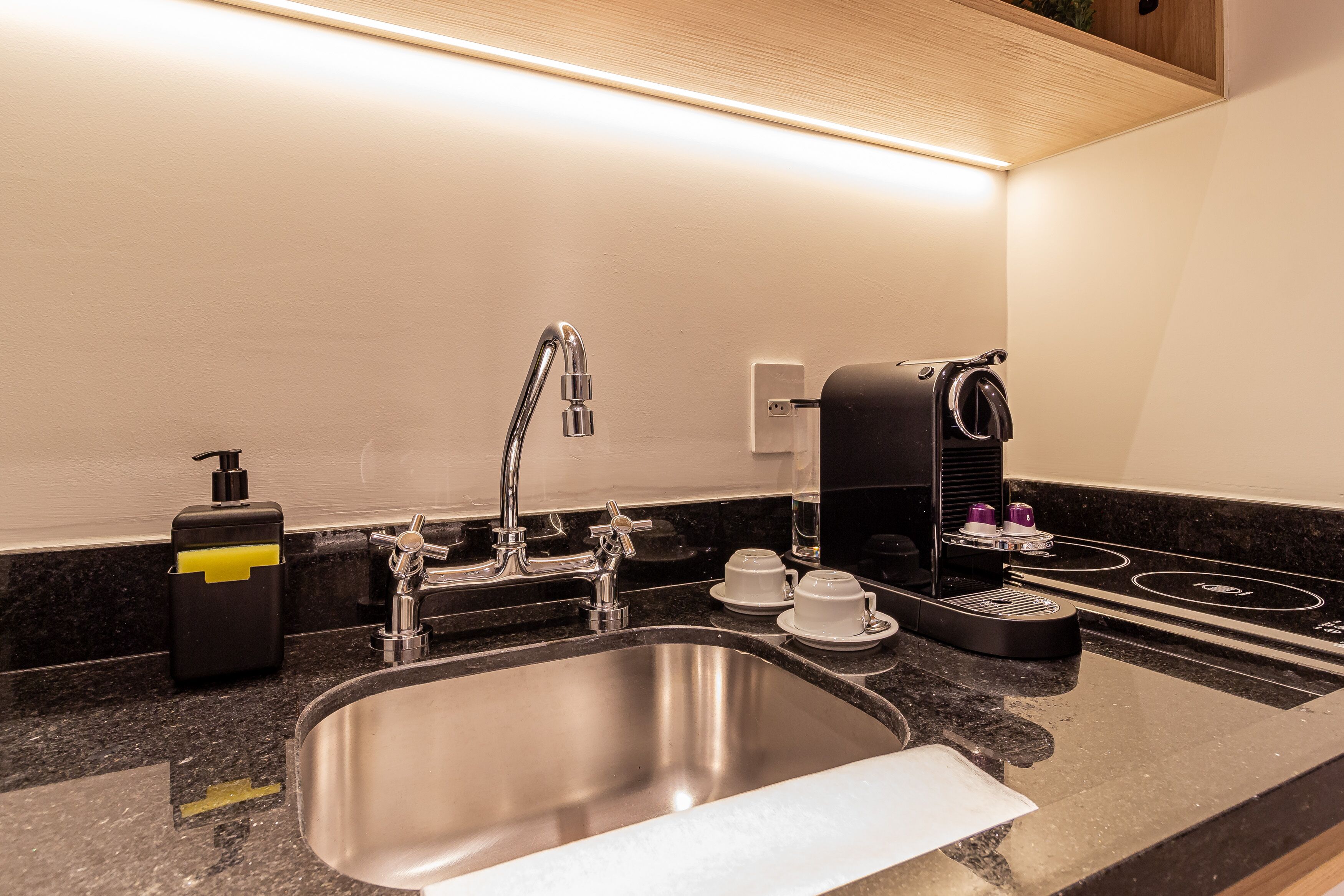 A modern kitchen with a stainless steel sink, a coffee maker, and a soap dispenser.