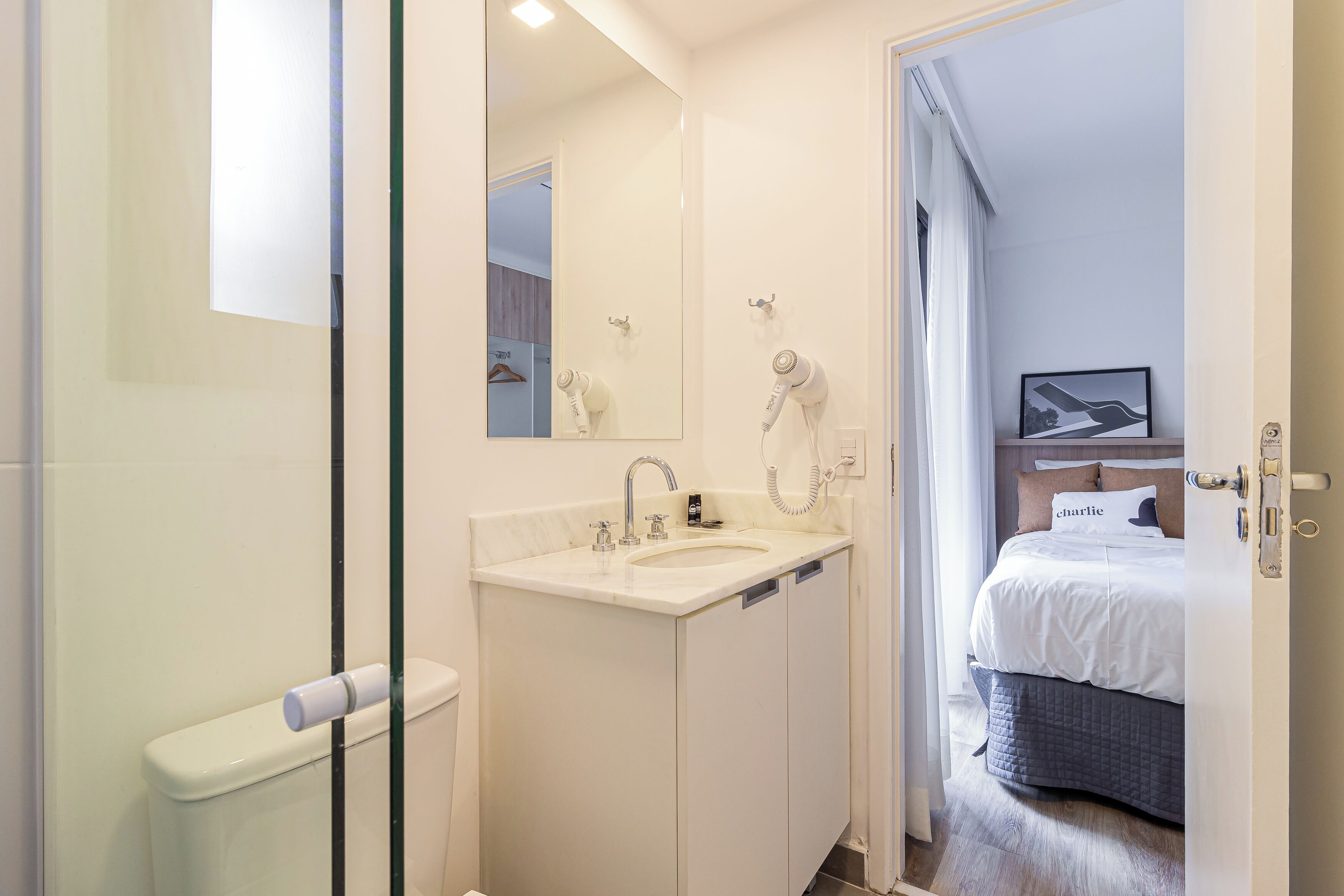 A modern bathroom with a glass shower enclosure, a white sink, and a mirror.
