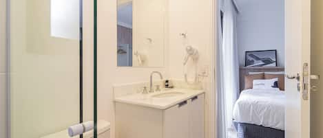 A modern bathroom with a glass shower enclosure, a white sink, and a mirror.