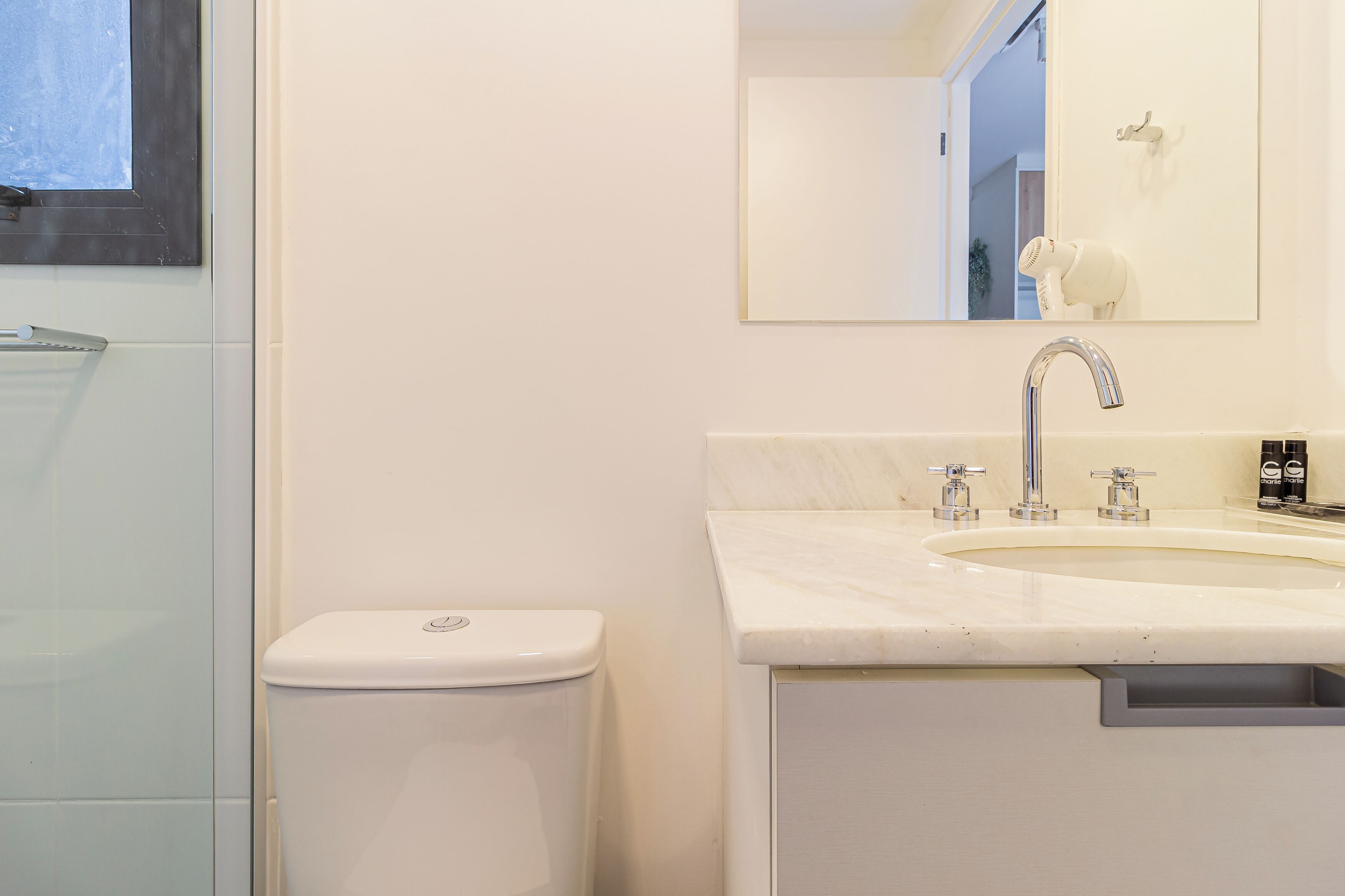 A bathroom with a toilet, a sink with a mirror, and a shower area.