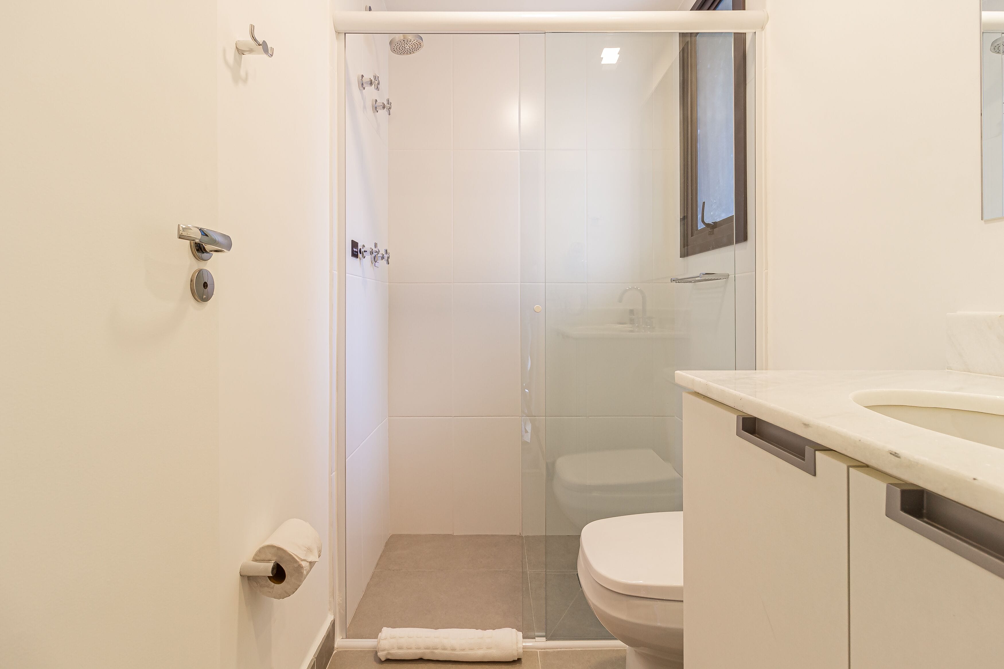A small, modern bathroom with a glass shower enclosure, a toilet, and a sink.