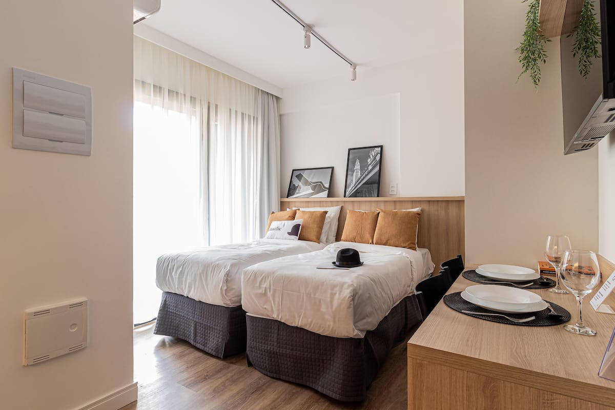 Ein Hotelzimmer mit zwei Betten, einem Esstisch mit Tellern und einem Weinglas sowie einem Fernseher an der Wand.