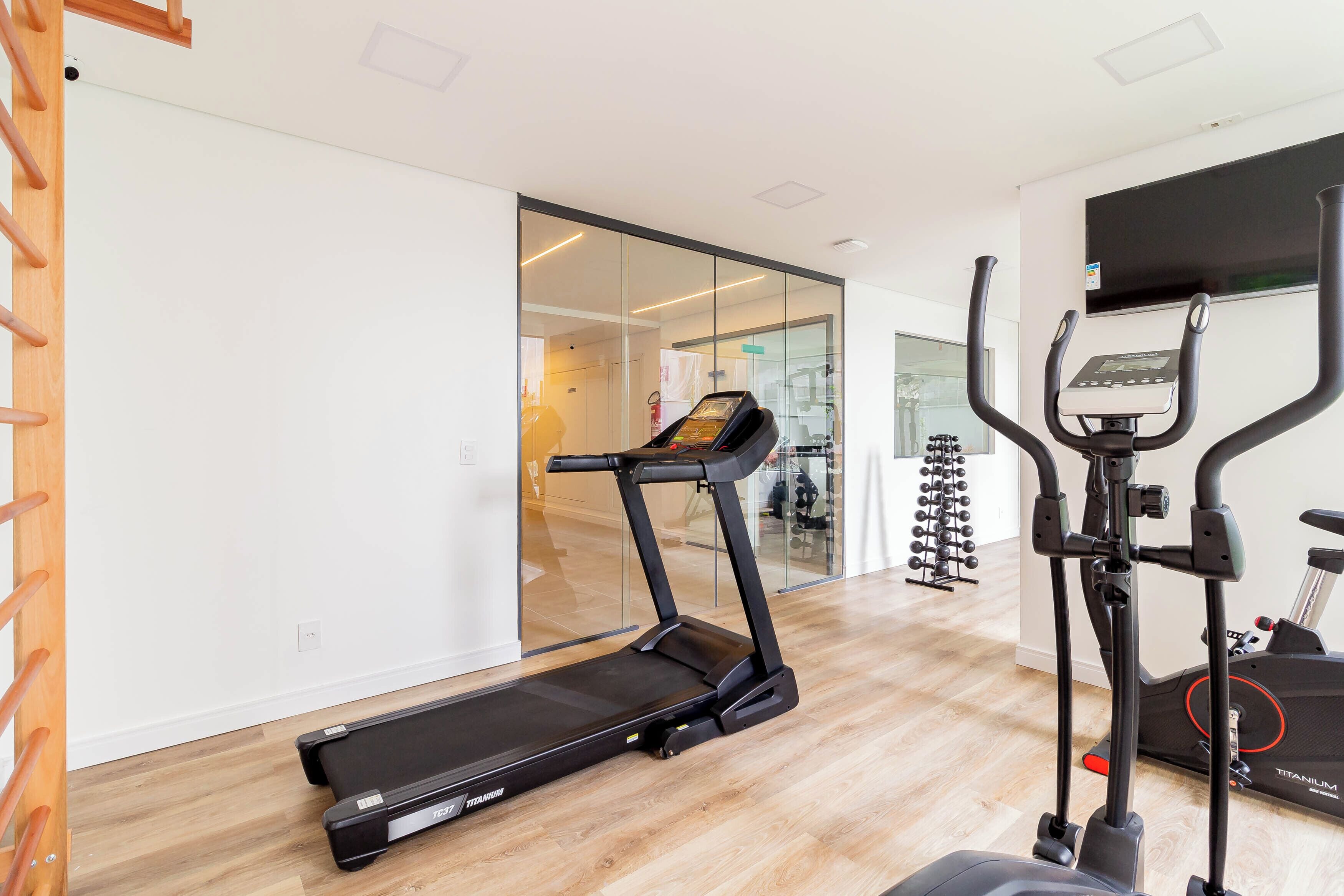 A modern gym with a treadmill, elliptical, and stationary bike.
