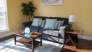 Ein Wohnzimmer mit Sofa, Couchtisch, Lampe und einem Bild an der Wand.