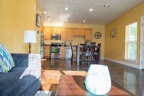 A modern kitchen with wooden cabinets, stainless steel appliances, and a dining area with dark chairs.