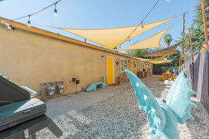 A building with a yellow exterior, outdoor seating area, and a small table. - Tribune at Redlands, Arcade Hands (Redlands)