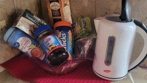 Una encimera de cocina con una tetera, varios alimentos y un paño rojo.