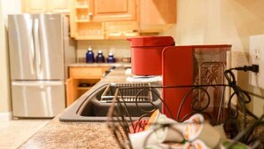 A kitchen with wooden cabinets, a stainless steel refrigerator, a red pot on the counter, and a dishwasher. - Unit F (Moss Point)