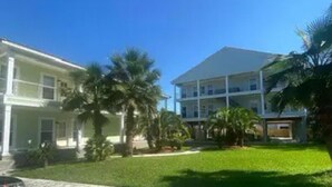 A two-story building with a flat roof and a large lawn area. - Unit F (Moss Point)
