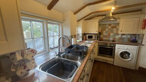 Een keuken met een granieten aanrecht, een roestvrijstalen spoelbak, oven, magnetron en een ingebouwde wasmachine.