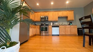 A kitchen with wooden cabinets, stainless steel appliances, and a potted plant. - Unit G (Moss Point)