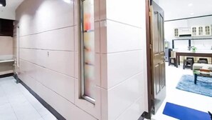Un corridoio moderno di un hotel, con una sala da pranzo visibile attraverso una porta aperta.