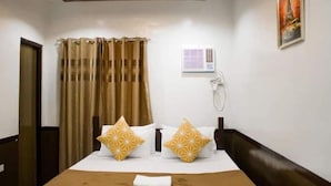 Camera d'albergo con un letto, tende, un telefono a muro e un quadro.