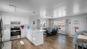 A modern kitchen with white cabinets, a central island, and a dining area with a table and chairs.