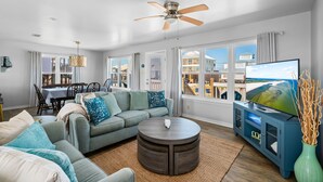 A modern living room with a sofa, coffee table, TV, and dining area.