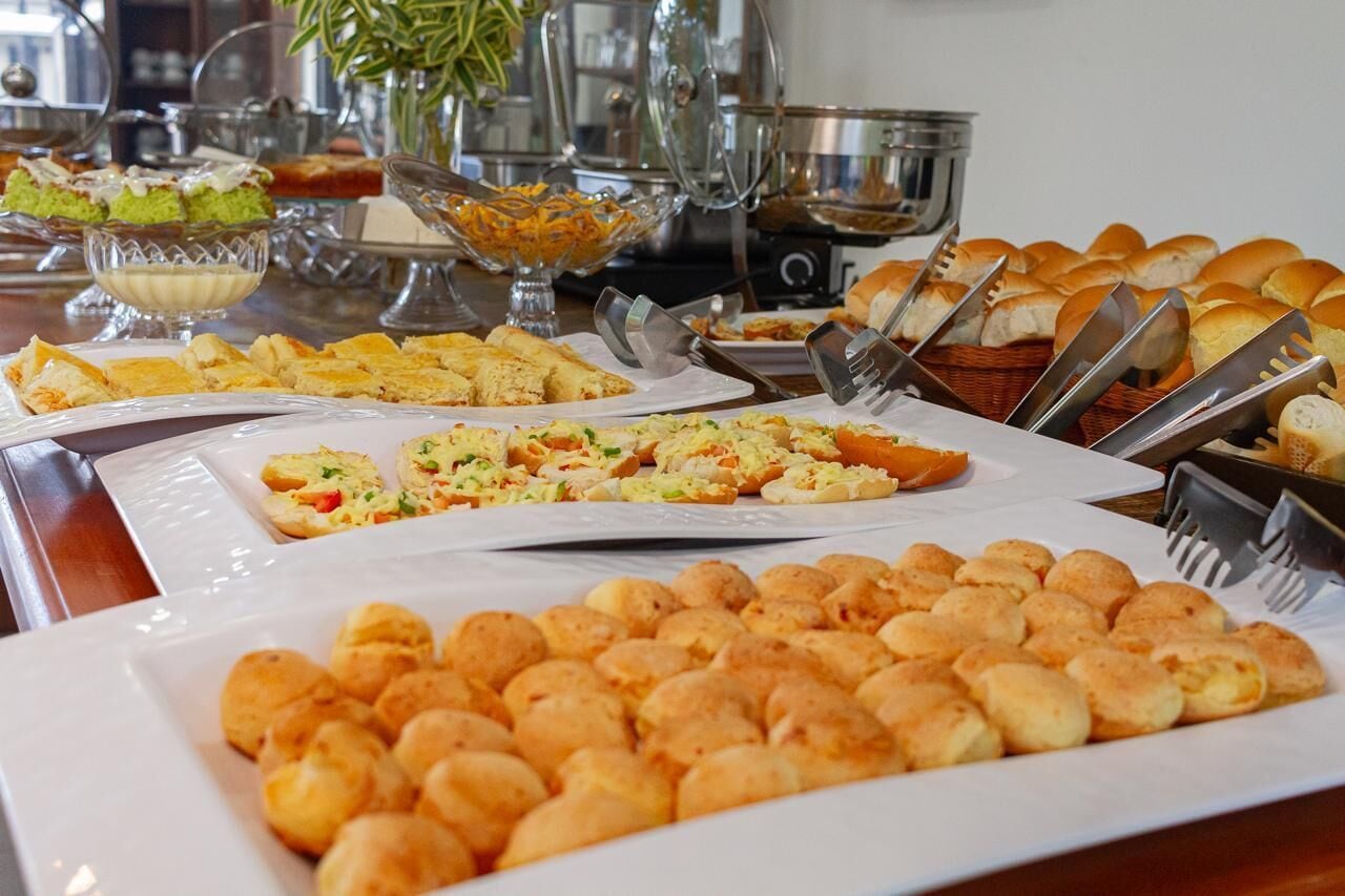 A buffet table with various food items including bread rolls, pastries, and a salad.