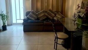 A living room with a sofa, a dining table, and a potted plant.