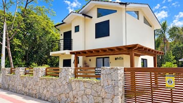 A two-story house with a stone wall and a wooden gate.