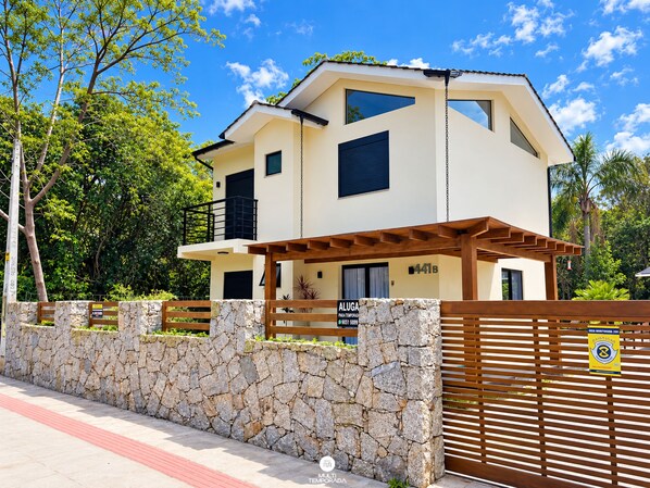 Una casa de dos pisos con un muro de piedra y un portón de madera.