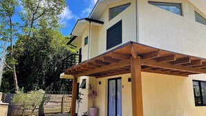 A modern two-story house with a covered patio area, large windows, and a wooden pergola. - Casa Privativa com Piscina na Ferrugem (Garopaba)