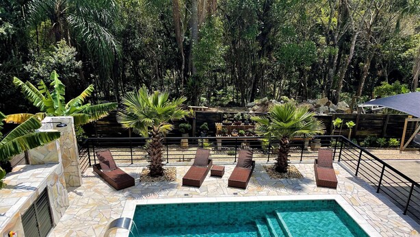 A swimming pool with lounge chairs and palm trees. - Casa Privativa com Piscina na Ferrugem (Garopaba)