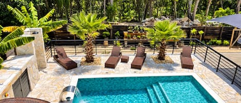 A swimming pool with lounge chairs and palm trees.