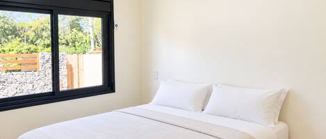 A bedroom with a bed, a window, and an air conditioning unit.