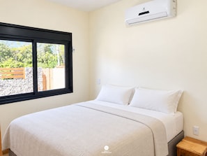 A bedroom with a bed, a window, and an air conditioning unit.