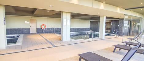 Uma piscina ao ar livre coberta, com bancos e um boia salva-vidas.