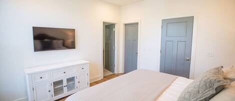 Un dormitorio con cama, cómoda blanca, ventilador de techo y dos puertas.