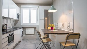 A modern kitchen with a microwave, oven, and washing machine. There is a dining area with a table and chairs. - Retiro VI Acogedor apartamento situado en Retiro (Madrid)