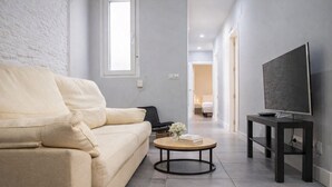 A modern living room with a beige sofa, a round coffee table, and a TV on a stand. - Retiro VI Acogedor apartamento situado en Retiro (Madrid)