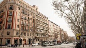 A multi-story building with balconies, a SkyPhone store, and parked vehicles on the street. - Retiro VI Acogedor apartamento situado en Retiro (Madrid)