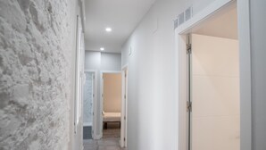 A hallway with a textured wall, a bed in the background, and a door with a white panel. - Retiro VI Acogedor apartamento situado en Retiro (Madrid)