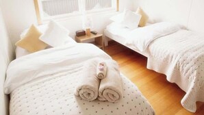 A hotel room with two beds, a nightstand, and a window.