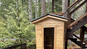 A wooden cabin with a glass door, a hot tub, and a wooden deck.