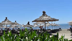 A beachside restaurant with thatched umbrellas and outdoor seating. - Cosmo Beach Hotel (Durrës)