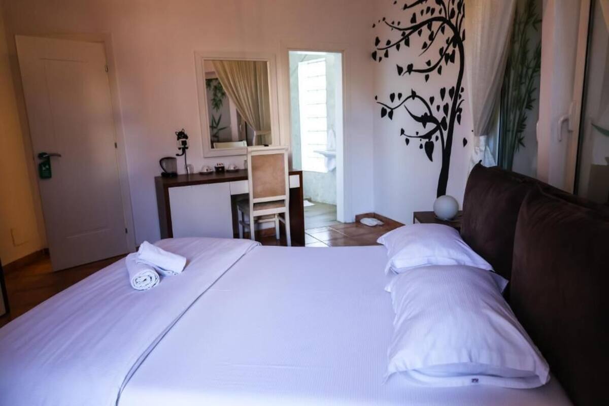 A hotel room with a bed, a desk, a chair, and a large window.