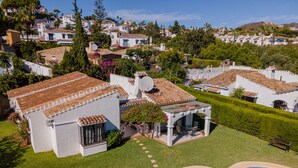 Un edifici residencial amb piscina, parets blanques i teulat de rajola.