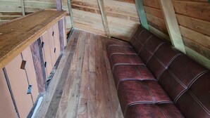Un dormitorio de ático con piso de madera, un banco y una mesa de madera.
