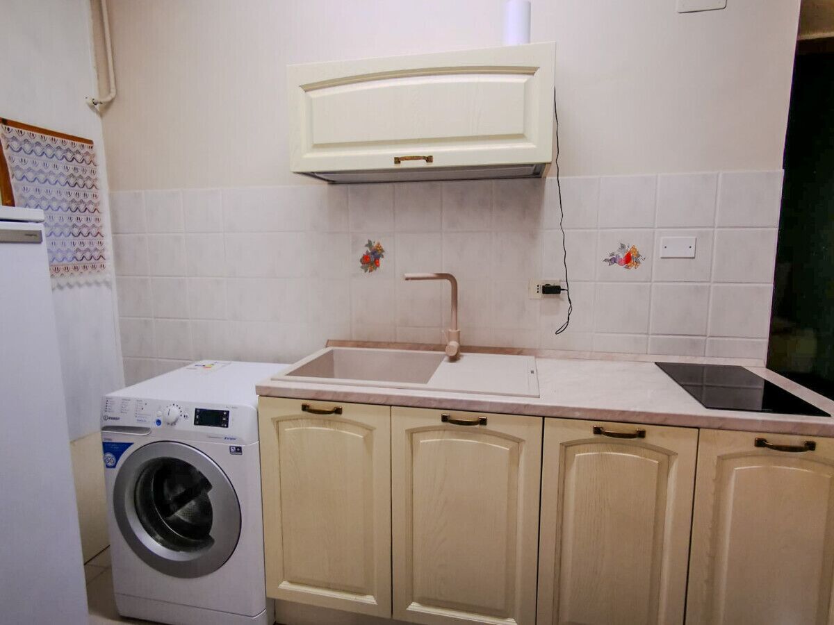 A compact kitchen with a washing machine, a sink, and cabinets.