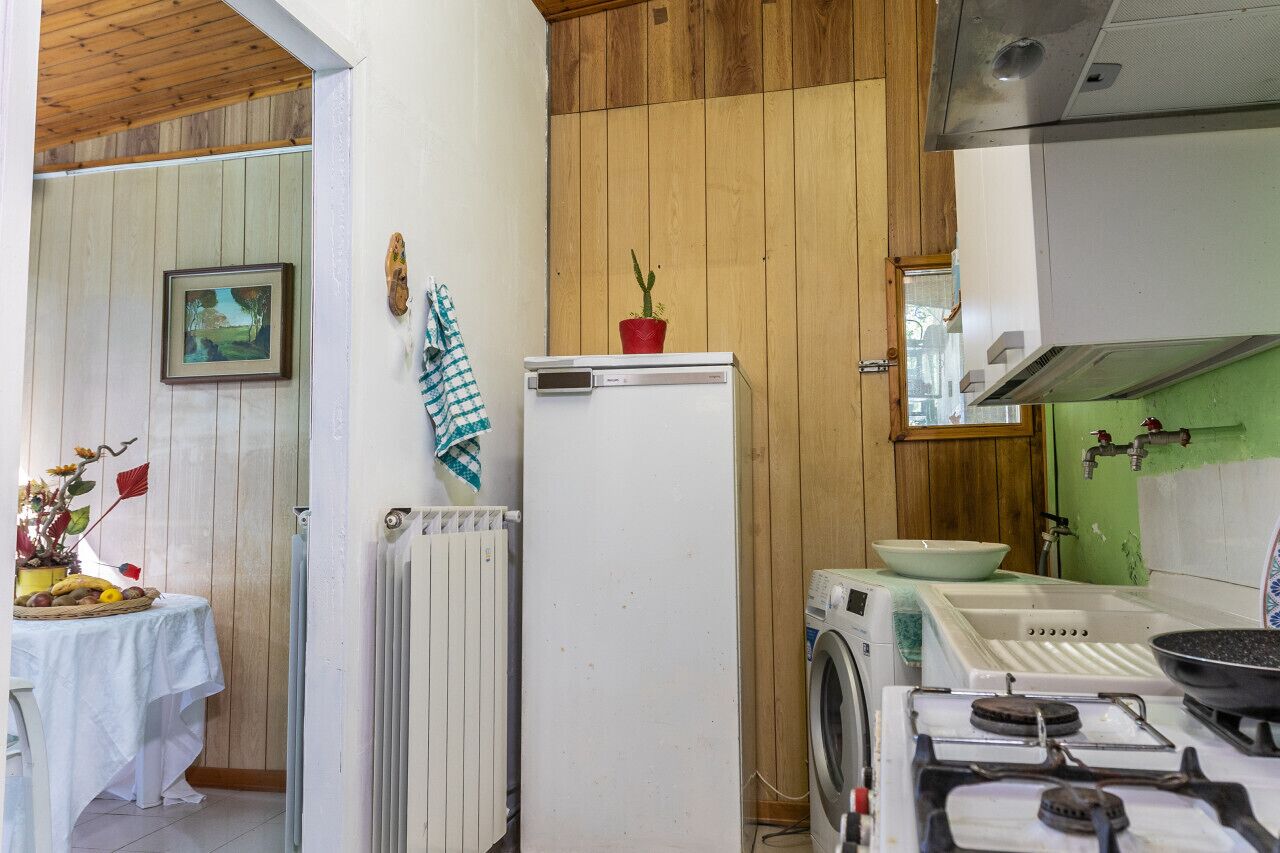 Een functionele keuken met een koelkast, fornuis en wasmachine.