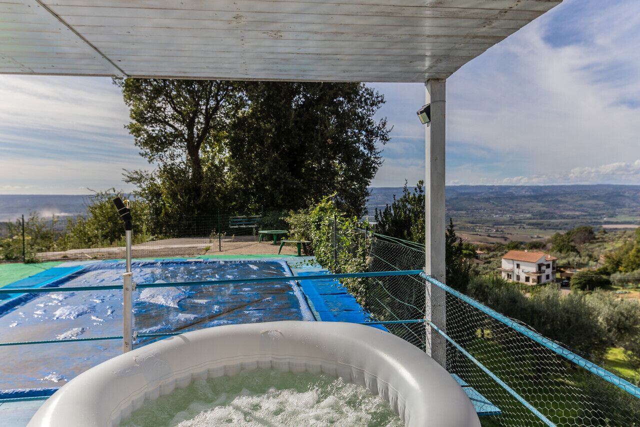 Un jacuzzi con vista a una piscina y una casa al fondo.