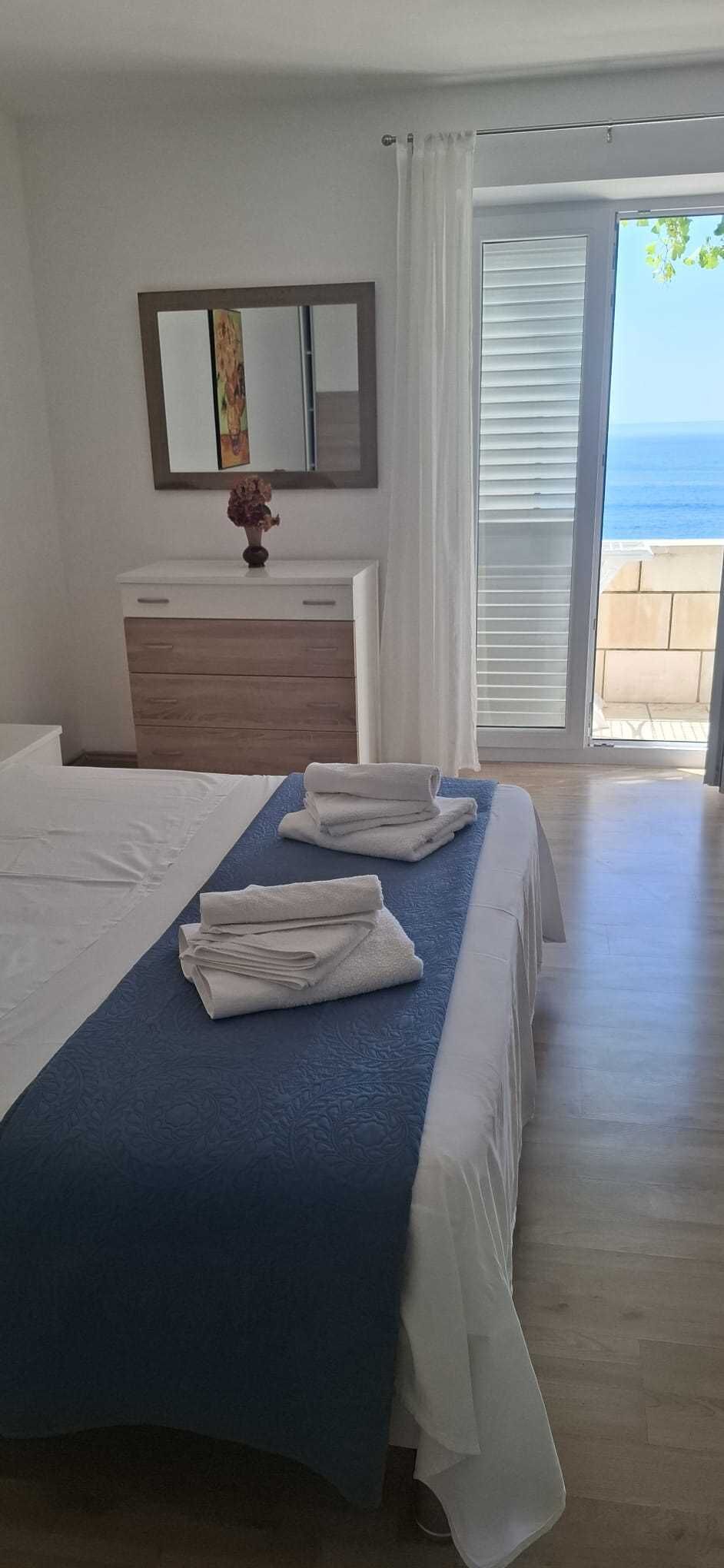 Habitación de hotel con cama, cómoda, espejo y vista al mar.