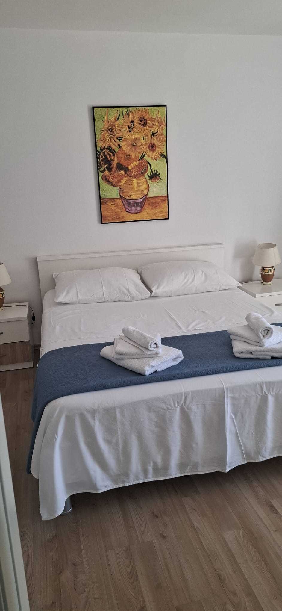Un lit bien fait, avec des draps blancs, une couverture bleue et des serviettes pliées.