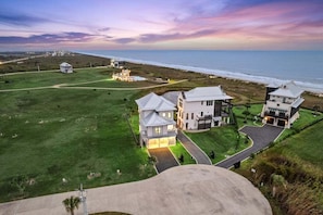 A coastal property with multiple buildings, a well-maintained lawn, and a view of the ocean. - Private Beach Neighborhood | Pool | Sleeps 12 (Gilchrist)