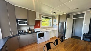 A modern kitchen with grey cabinets, a wooden dining table, and a built-in microwave. - Twizel Tranquility, FREE Wi-Fi (Twizel)