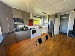 A modern kitchen with grey cabinets, a wooden dining table, and a built-in microwave.